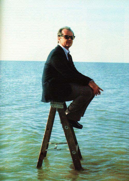 Man i kostym på stege ute i havet