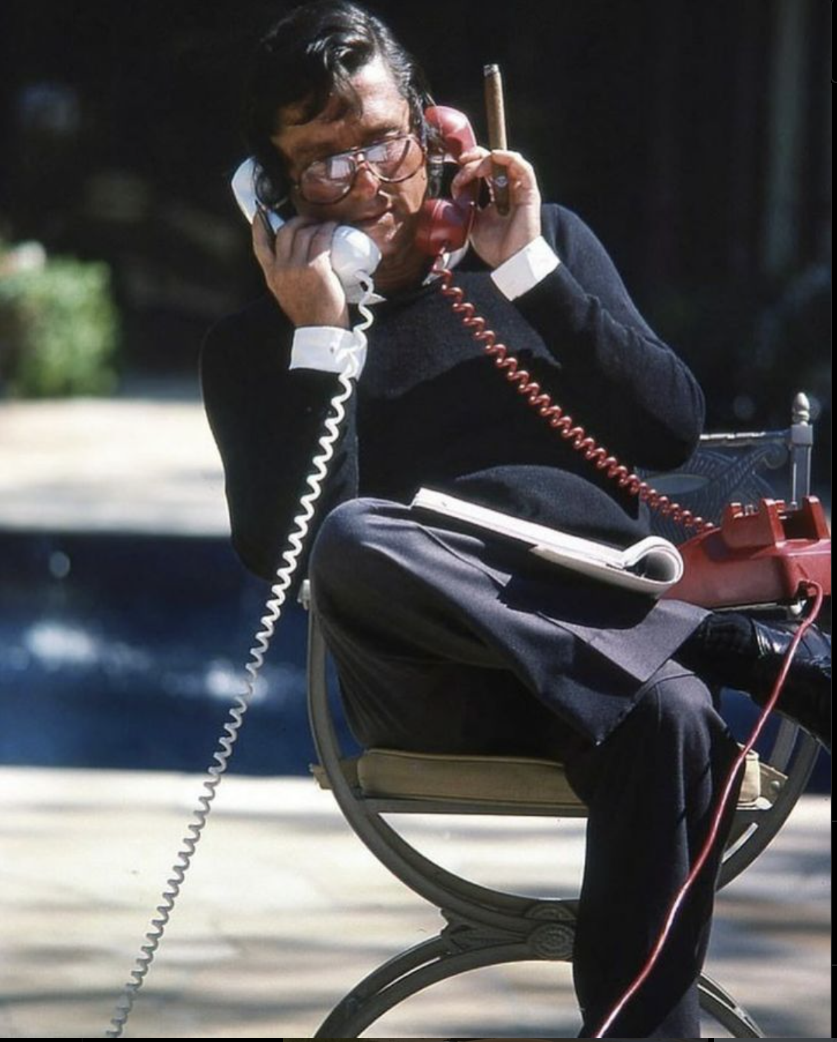 Man med två telefonlurar och cigarr vid poolen